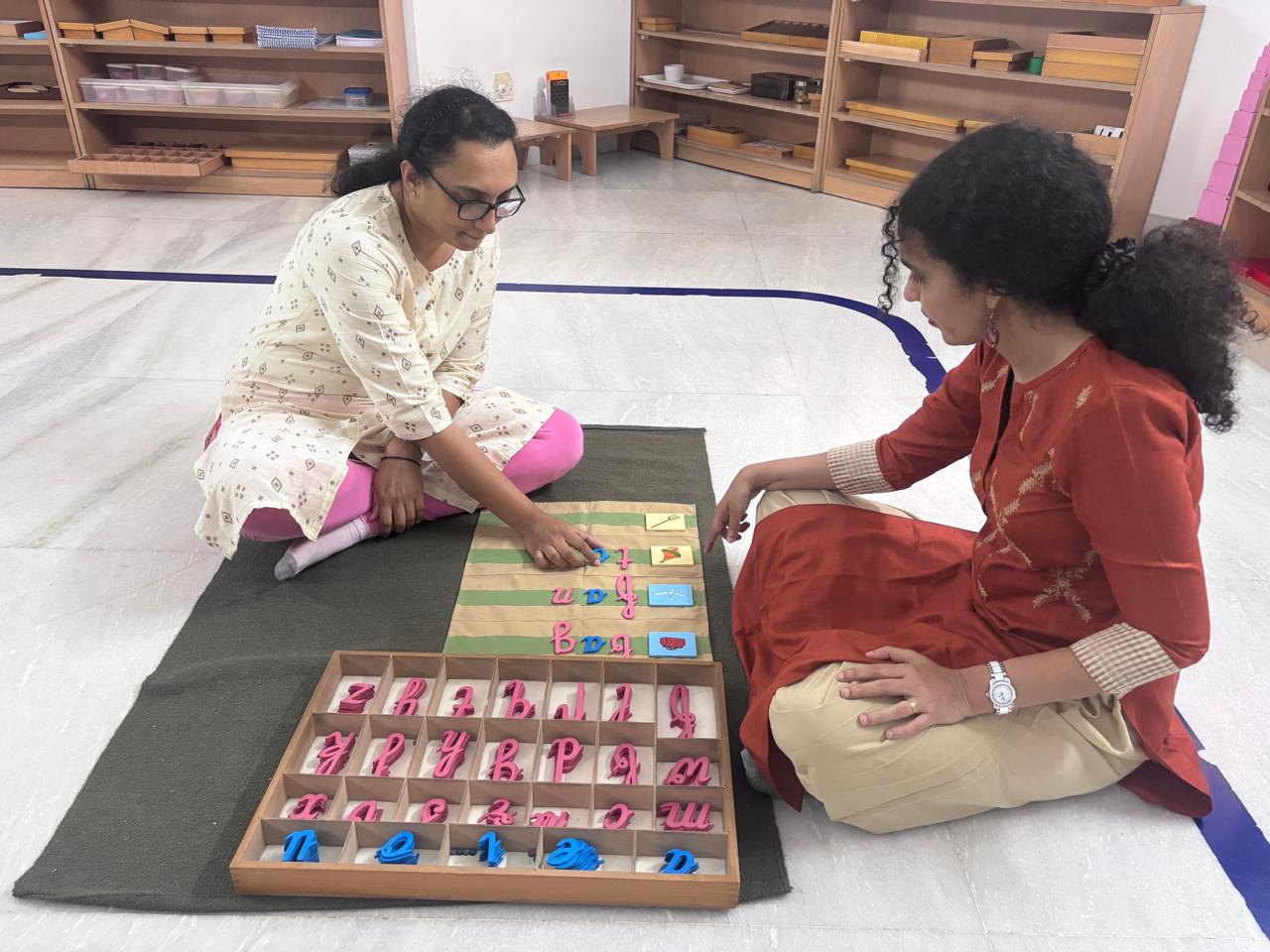 Trainer supporting a trainee with bead board material in Montessori teacher training